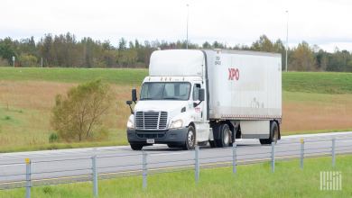 A white XPO tractor pulling a trailer on a highway