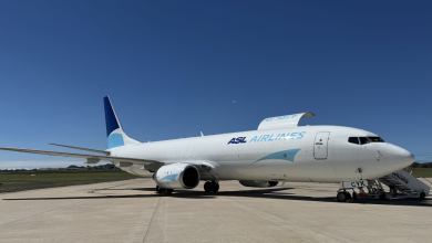 A 737-800 cargo jet with light-and-dark blue accents rests on the tarmac on a sunny day.