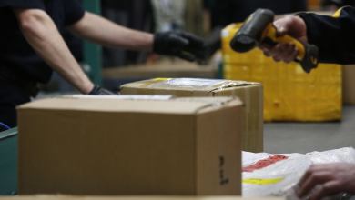 Inspectors using bar code scanner to check parcels for contrand.