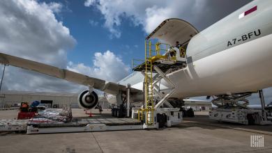Close up of large jetliner with cargo door open, view from the tarmac behind the wing.