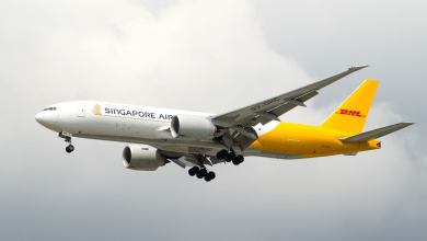 A freighter with the dual logos of Singapore Airlines and DHL approaches an airport for landing.