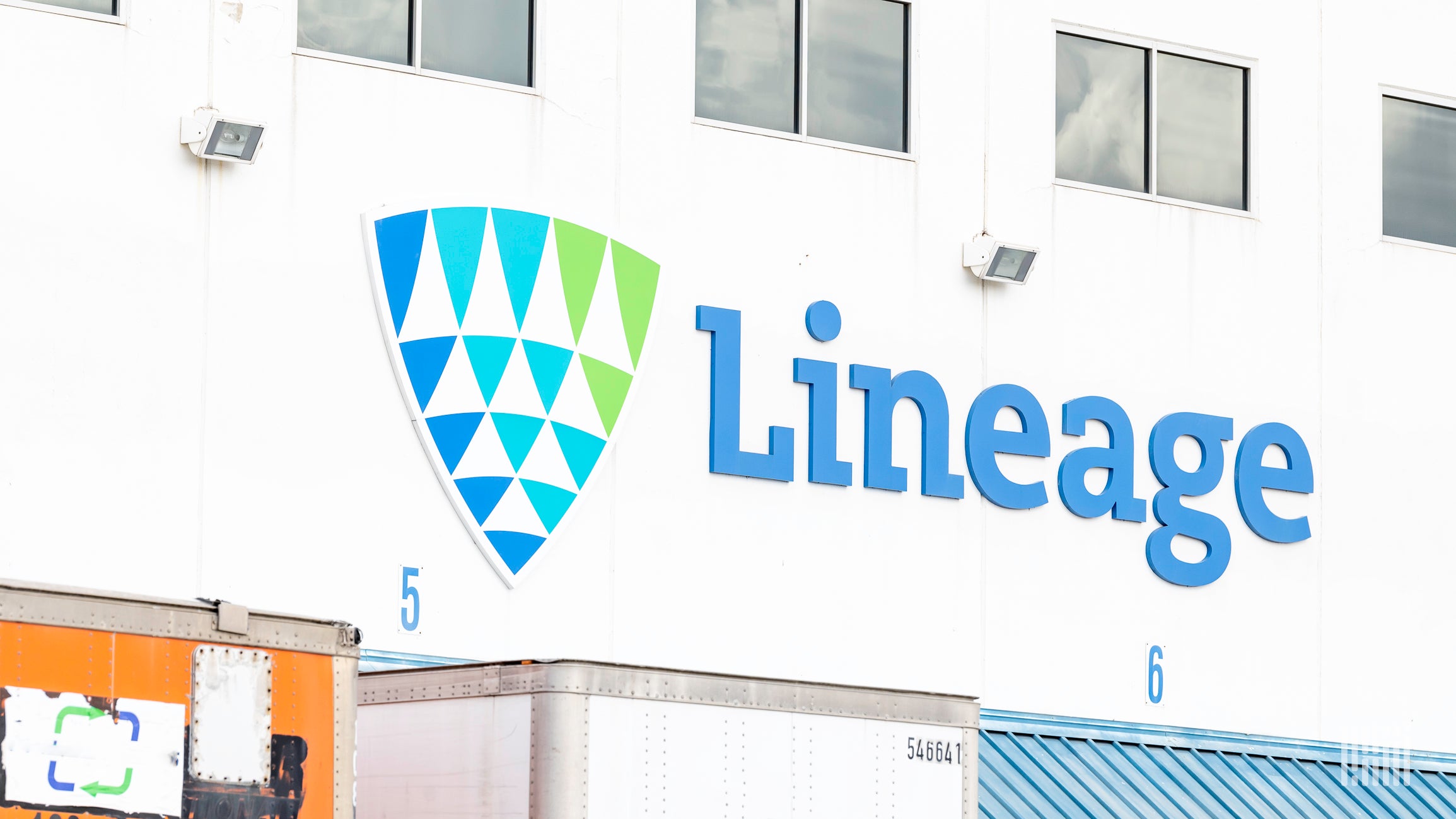 'Lineage' logo on the side of a warehouse with trailers parked beneath