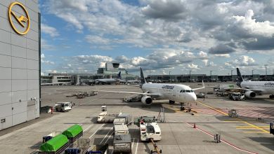 A Lufthansa passenger jet pulls into a terminal gate area on a sunny day.