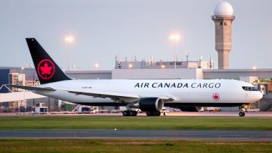 Air Canada Cargo jet with black tail and red Canadian maple leaf on the ground at an airport.
