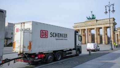 Image shows a Schenker truck and Berlin's Brandenburg Gate.