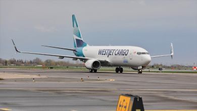 A teal-tailed WestJet Cargo plane rolls on the taxiiway on a gray day.