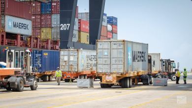 Images shows trucks, containers and container crane.
