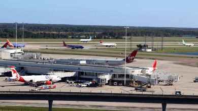 Jet aircraft at the gate and on the taxiway at a large airport on a sunny day.