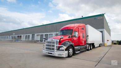 A red tractor with a white trailer backed up to a Prologis dock door