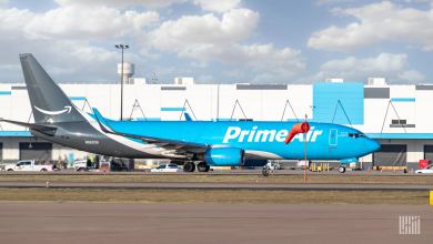 A light-blue Prime Air cargo jet taxis at an airport.