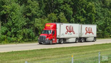 A red Saia daycab pulling two Saia pup trailers