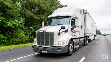 A white Pam tractor pulling a white Pam dryvan trailer on a highway