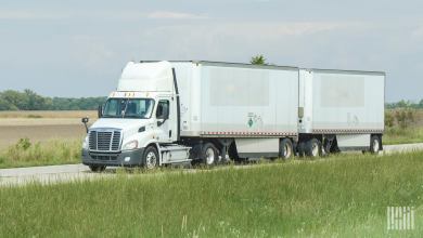 A white daycab pulling two white pup trailers on a highway