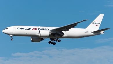 A white jet with CMA CGM Air Cargo lettering with wheels down for landing.