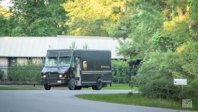 A brown UPS delivery van on a tree-lined neighborhood street.
