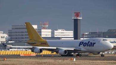 A Polar cargo plane with blue lettering and a gold DHL tail area sits on the runway.