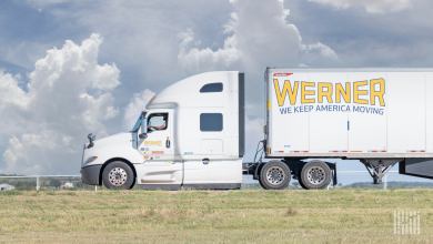sideview of a parked Werner tractor-trailer with a driver