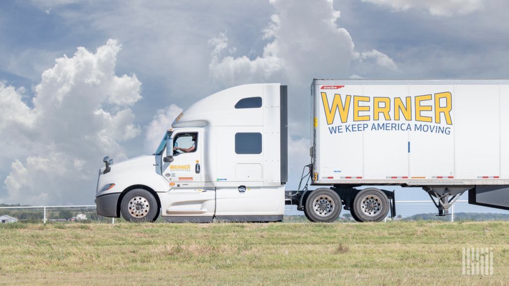 sideview of a parked Werner tractor-trailer with a driver