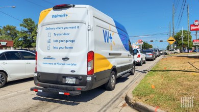 A Walmart delivery van on a major road, as seen from the rear.