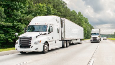 A white sleeper cab pulling a white refrigerated trailer on a highway