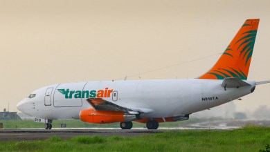 A small Transiar cargo jet with orange and green trim rolls on a runway in Hawaii.