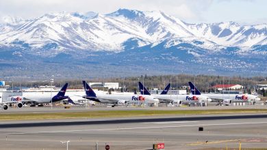 FedEx cargo aircraft on the ramp at Anchorage airport with snow-covered mountains in the background.