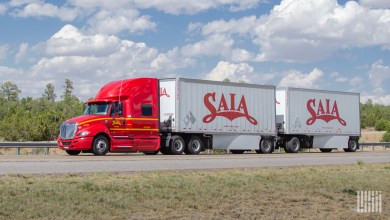 A red Saia sleeper cab pulling two Saia pup trailers