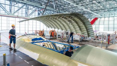 A worker walks on top of an large jet undergoing a passenger-to-freighter modification in a hangar.