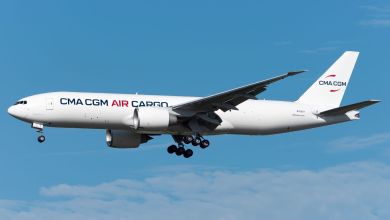 A white CMA CGM Air Cargo jet seen flying, side view.