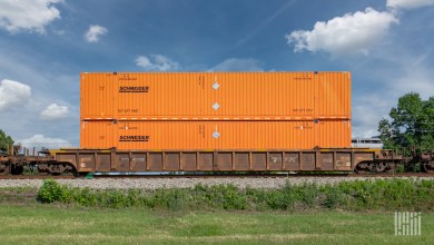 Orange Schneider double-stacked intermodal containers moving on a TTX well car