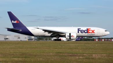 A purple/orange/white FedEx freighter lands at an airport.
