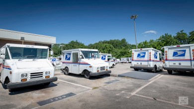 Mail delivery vans are parked in a U.S. Postal Service parking lot.
