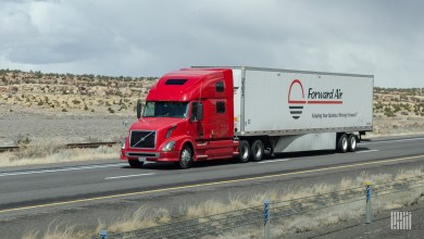 a red sleeper cab pulling a white Forward Air trailer