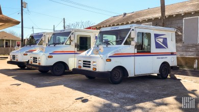 Three U.S. Postal Service delivery vans are parked in front of a small neighborhood post office.