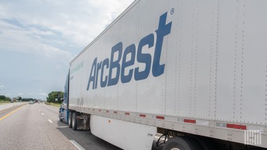 A sideview of an ArcBest trailer being pulled on a highway