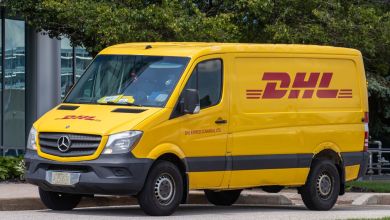 A bright-yellow DHL delivery van parked on a street.