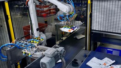 A robotics arm helps sort packages on a FedEx package conveyor.