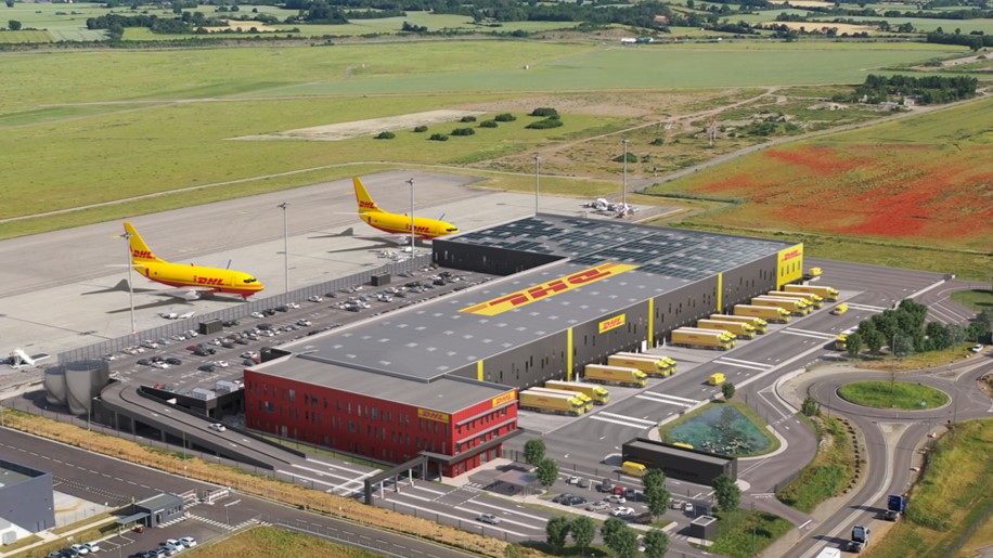 Aerial view of a DHL air cargo terminal with mustard-colored planes parked next to it.