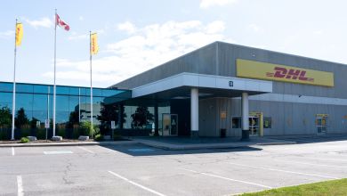 DHL headquarters building with yellow-red signage and flag poles with Canadian flag.