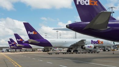 Purple-tailed FedEx planes in a row at an airport.