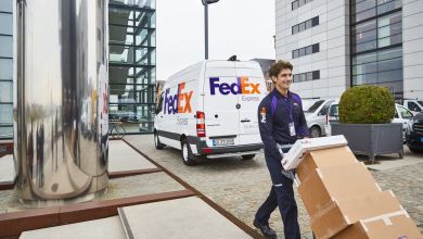 A FedEx driver pushes a handcart with packages after loading up from his van.