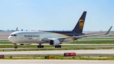 A brown-tailed UPS cargo jet taxis at an airport on a sunny day.