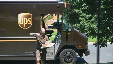 A UPS driver scans a package after exiting brown delivery truck.
