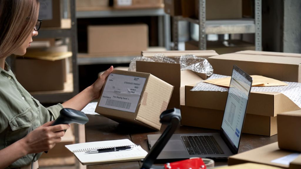 A woman weighs a package and affixes a label before shipping it.
