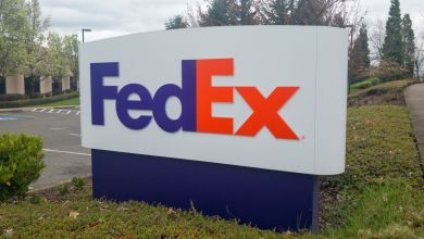 Close up of a purple-orange FedEx sign on lawn of business park.