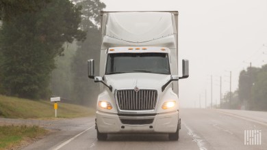 Front view of a white tractor pulling a trailer on a highway