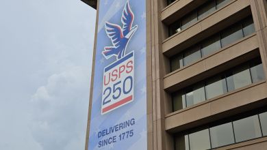 Large blue sign on side of a high-rise building, with the USPS eagle to celebrate the USPS's 250th anniversary.