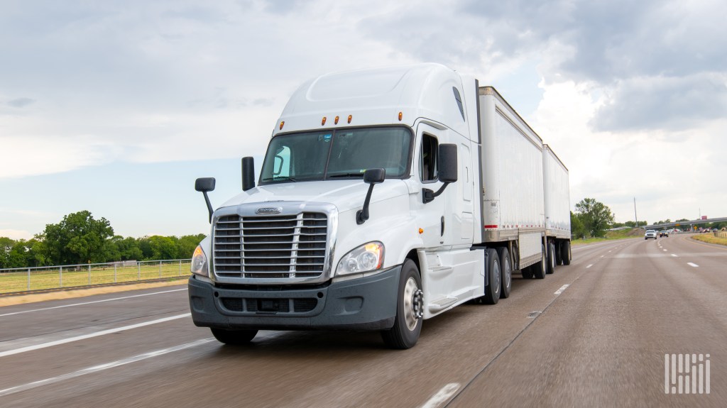 A white sleeper cab pulling two white LTL pup trailers