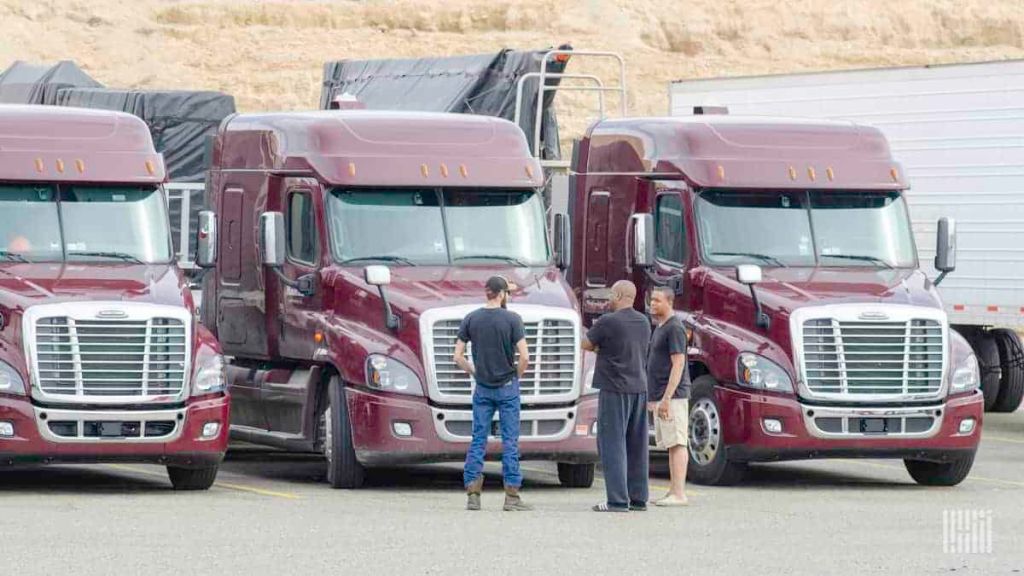 truck drivers talking in front of trucks at a truck stop