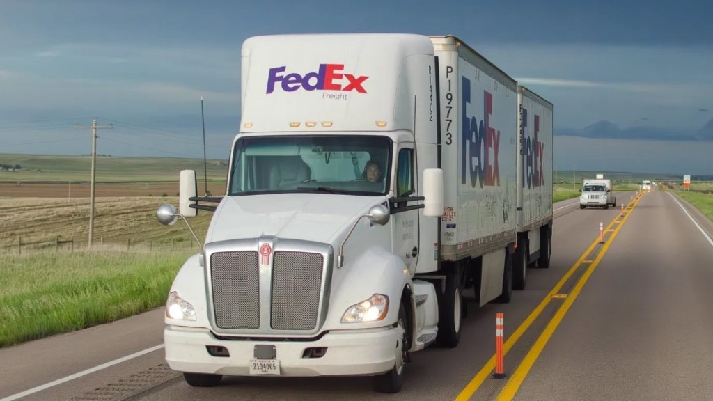 A white FedEx Freight tractor pulling two FedEx pup trailers